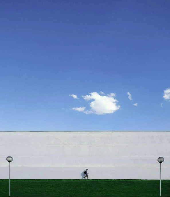 a person walking in front of a white wall, by Jan Rustem, epic blue sky, a park, competition winning, environments )