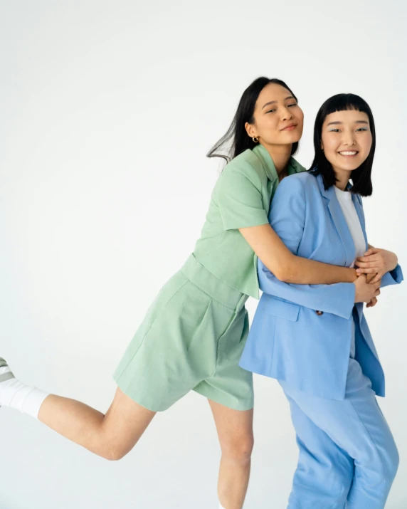 a couple of women standing next to each other, inspired by Wang Duo, trending on unsplash, blue and green colours, wearing a light blue suit, standing on two legs, pride month