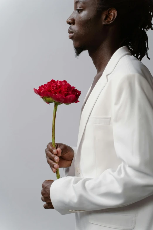 a man in a white suit holding a red rose, an album cover, inspired by Theo Constanté, trending on unsplash, tall flowers, african man, profile image, zoomed in