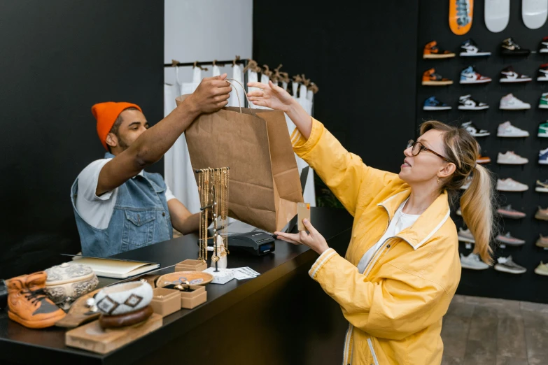 a man and a woman are shopping in a shoe store, pexels contest winner, wearing a yellow hoodie, delivering parsel box, wearing an orange t shirt, brown paper