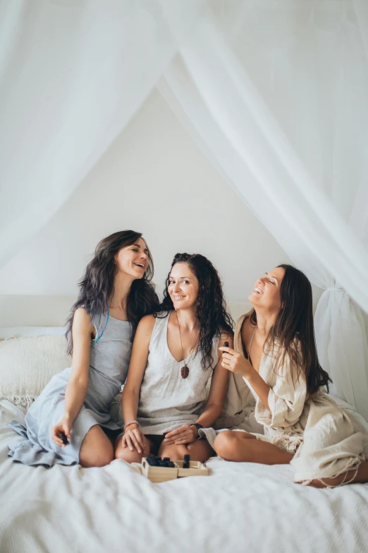 a group of women sitting on top of a bed, pexels contest winner, romanticism, playful smile, boho chic, three women, white backround