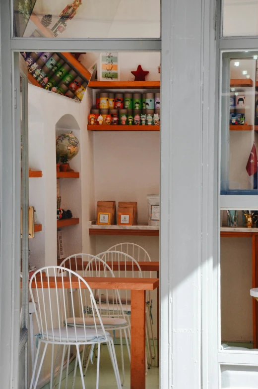 a kitchen that has a table and chairs in it, cute bakery shop, santorini, jar on a shelf, exterior shot