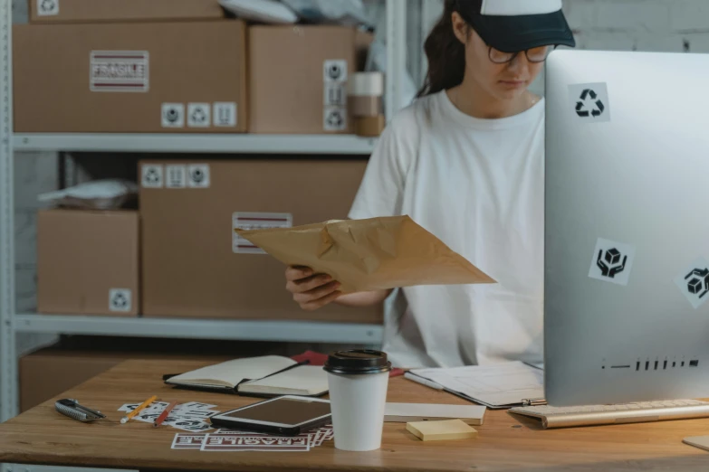 a woman sitting at a desk in front of a computer, pexels contest winner, delivering packages for amazon, small hipster coffee shop, avatar image, bulky build