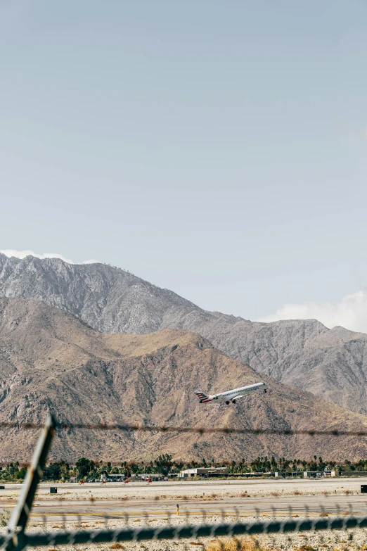 a plane taking off from an airport with mountains in the background, a picture, unsplash, visual art, palm springs, wide film still, 7 0 mm photo, 4 k