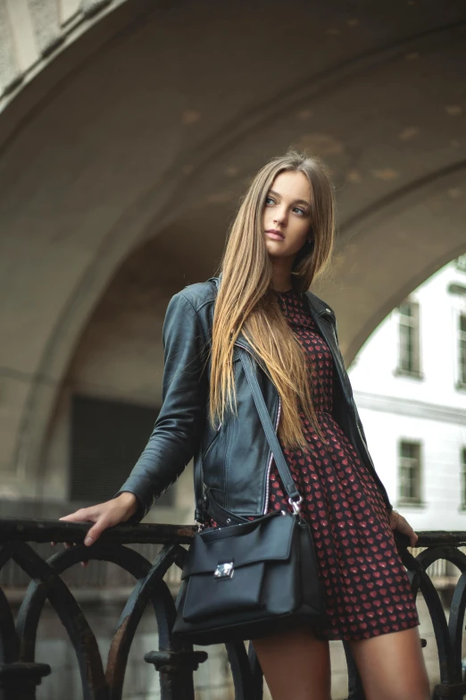 a woman standing on a bridge holding a purse, pexels contest winner, renaissance, wearing leather jacket, young with long hair, portait image, dress