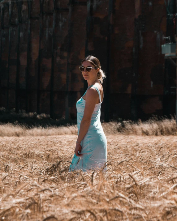 a woman standing in a field of wheat, inspired by Elsa Bleda, unsplash contest winner, color field, standing in abandoned building, slightly tanned, wearing blue sunglasses, wearing a white sundress