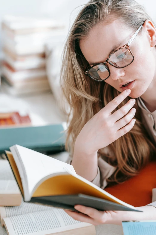 a woman laying on the floor reading a book, trending on pexels, academic art, square rimmed glasses, hand on her chin, post graduate, thinking