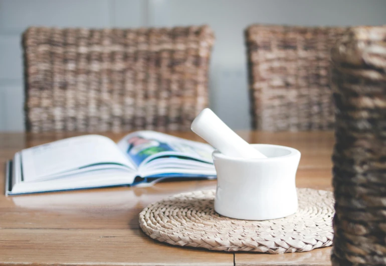 a mortar and a book on a table, by Charlotte Harding, glossy white, pestle, easy to use, long