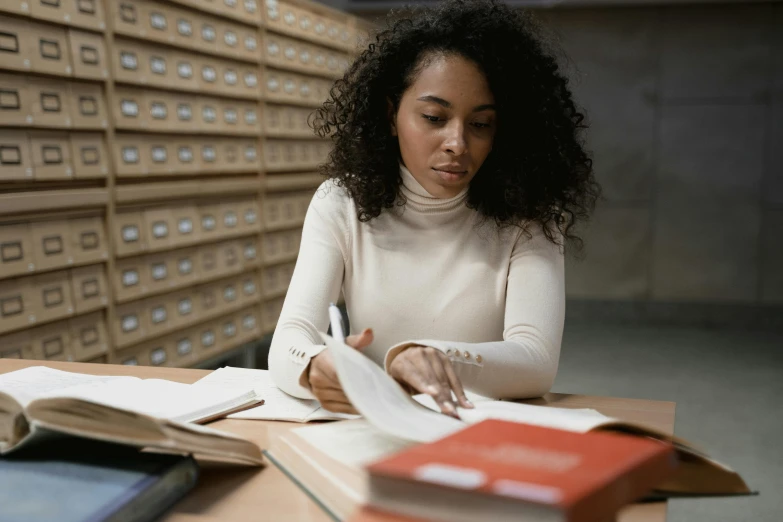 a woman sitting at a table reading a book, pexels contest winner, academic art, inspect in inventory image, black young woman, high quality screenshot, small library