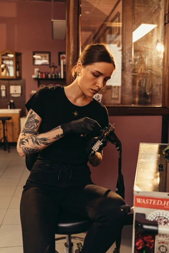 a woman sitting on a stool with a tattoo machine, a tattoo, trending on pexels, process art, aussie baristas, plating, looking serious, down left arm and back