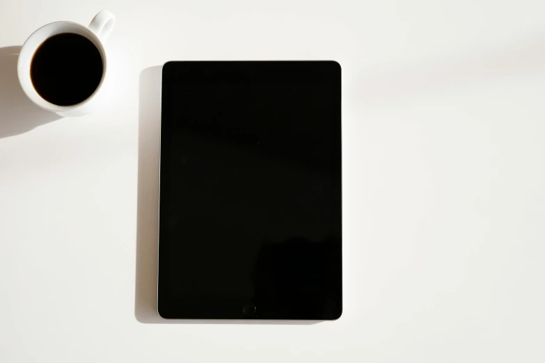 a cell phone sitting on top of a table next to a cup of coffee, a computer rendering, by Carey Morris, minimalism, ipad pro, white and black color palette, square, taken with sony alpha 9