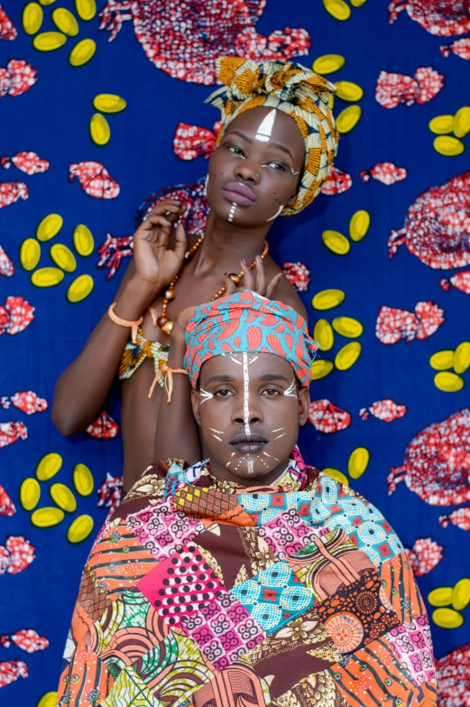 a couple of people laying on top of a bed, an album cover, by Ingrida Kadaka, trending on unsplash, afrofuturism, tribal facepaint, patterned clothing, yasuke 5 0 0 px models, somali attire