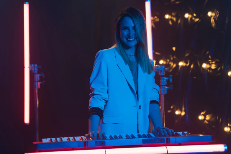 a woman standing next to a keyboard on a stage, pexels, happening, neon operator margot robbie, emma roberts, still from a music video, a still of a happy