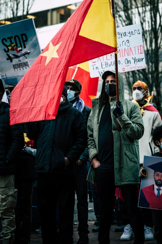 a group of people holding flags and signs, by Julia Pishtar, asian man, background image, belgium, masks