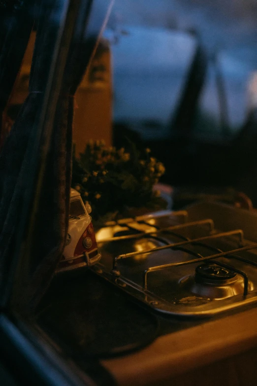 a stove top sitting on top of a wooden table, a still life, sitting on the beach at night, inside of a car, glamping, low quality photo