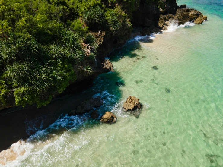 a large body of water next to a lush green hillside, pexels contest winner, hurufiyya, standing on a beach in boracay, rocky cliff, aerial iridecent veins, conde nast traveler photo