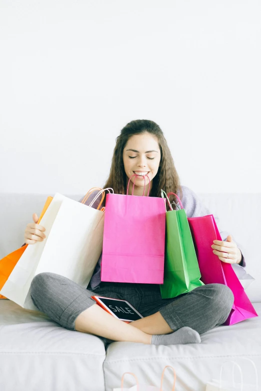 a woman sitting on a couch holding shopping bags, vibrantly colorful, online, 8 l, malls