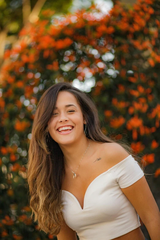 a beautiful young woman standing in front of a tree, by Olivia Peguero, happening, while smiling for a photograph, white and orange, asher duran, brown haired
