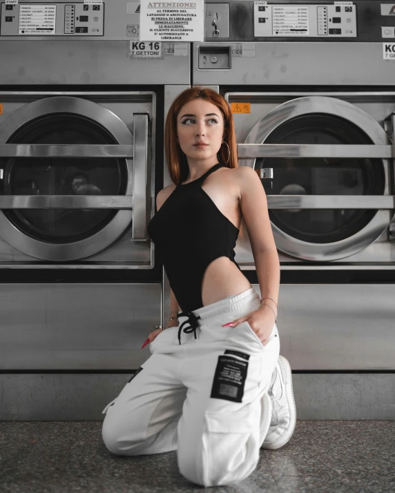 a woman sitting in front of a row of washing machines, by Cosmo Alexander, trending on pexels, better known as amouranth, wearing human air force jumpsuit, wearing a cropped black tank top, wearing white leotard