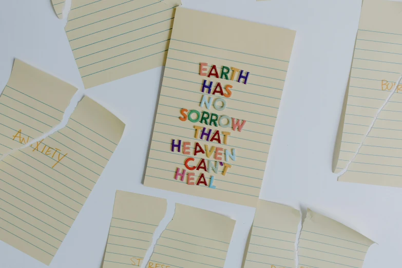 a bunch of sticky notes sitting on top of a table, by Robbie Trevino, unsplash, conceptual art, the tarot card of earthly demise, earth and pastel colors, detailed letters, paper cut out