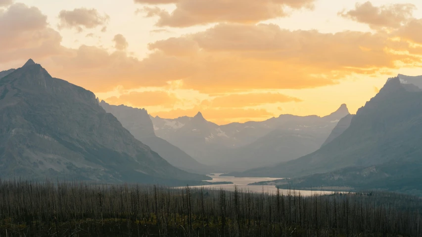 a view of a mountain range with a lake in the foreground, by Jessie Algie, pexels contest winner, sunset in a valley, glacier national park, patches of yellow sky, conde nast traveler photo