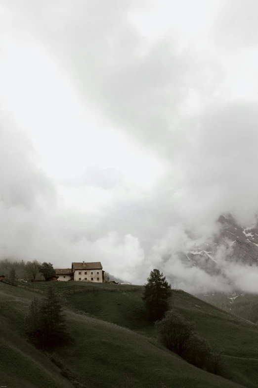 a house sitting on top of a lush green hillside, a matte painting, pexels contest winner, renaissance, gloomy moody clouds, alp