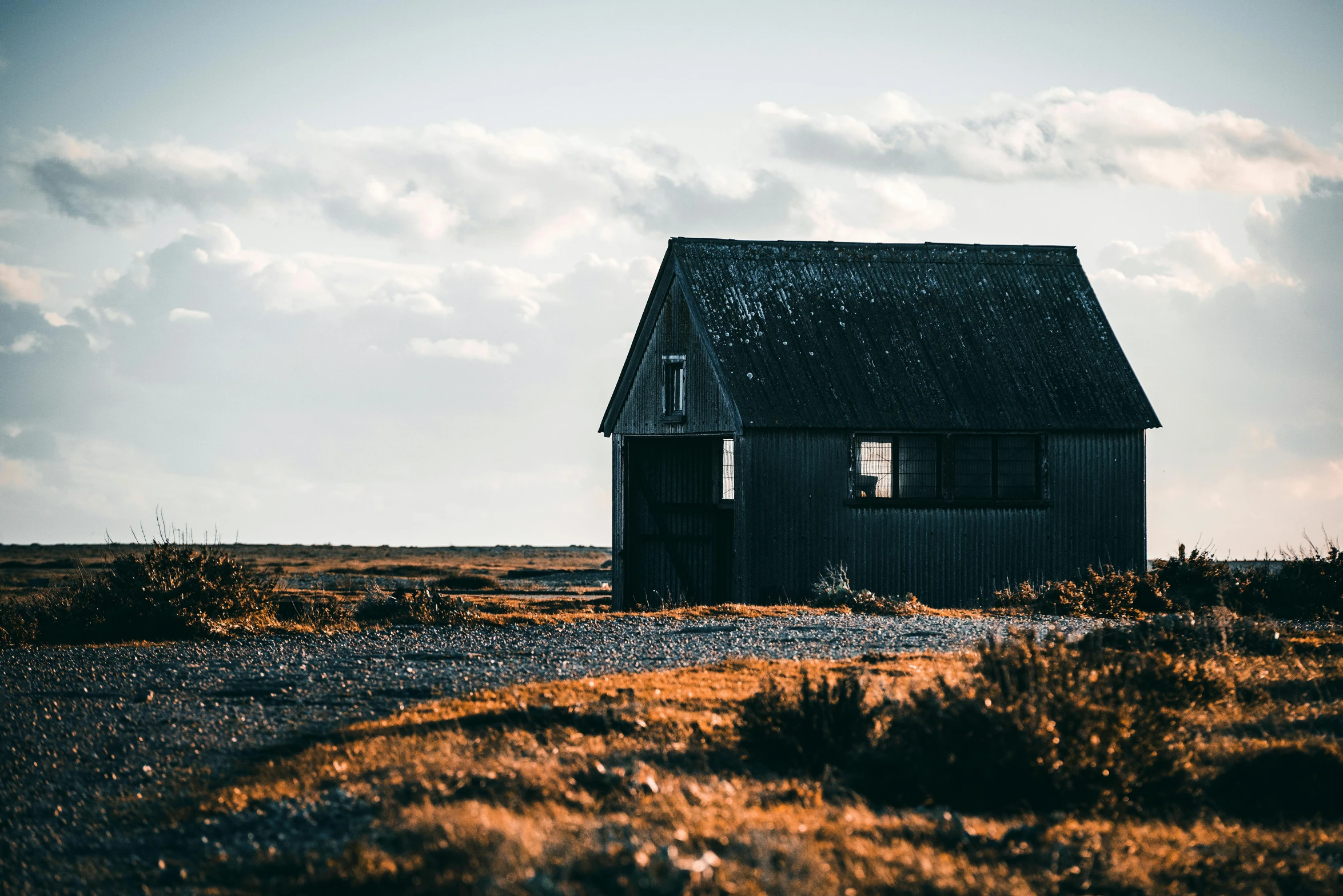 a small house sitting in the middle of a field, unsplash, profile image, rugged, shoreline, wooden structures