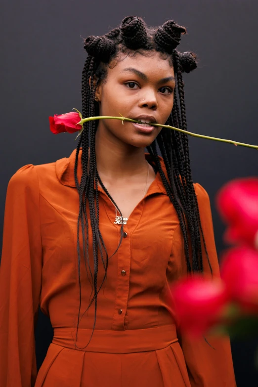 a woman holding a rose in front of her face, by Lena Alexander, pexels contest winner, box braids, at a fashion shoot, tall flowers, black teenage girl