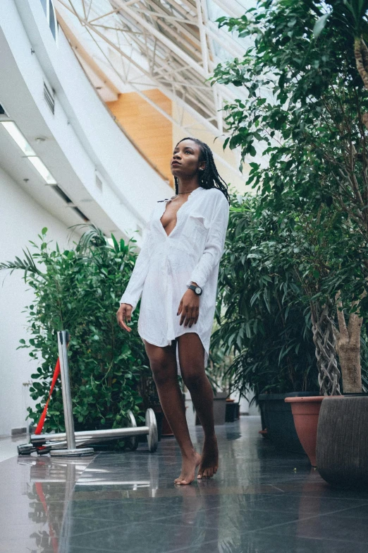 a woman in a white shirt standing in a building, pexels contest winner, sexy black woman walks past them, bathrobe, full body! pretty face, poolside