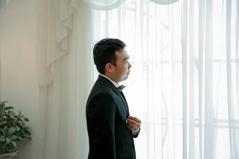 a man in a tuxedo adjusting his bow tie, inspired by Fei Danxu, looking out window, profile image, wedding photo, standing in corner of room