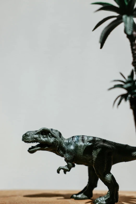 a toy dinosaur standing next to a palm tree, a statue, trending on unsplash, realism, low quality photo, t - rex, in profile, high angle close up shot