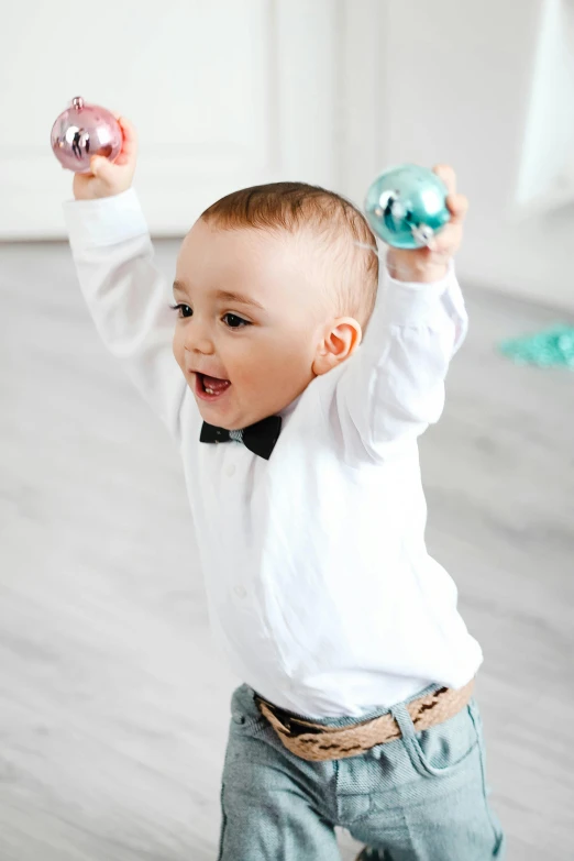 a baby in a bow tie playing with a christmas ornament, inspired by Master of the Bambino Vispo, happening, party balloons, award - winning details, flying black marble balls, activity play centre