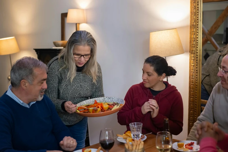 a group of people sitting around a table eating food, carrying a tray, profile image, at home, servando lupini