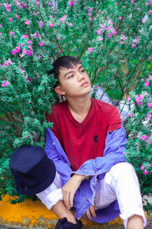 a man sitting on a curb next to a bush, an album cover, inspired by Chen Chi, androgynous face, multicolored, profile image, asian human