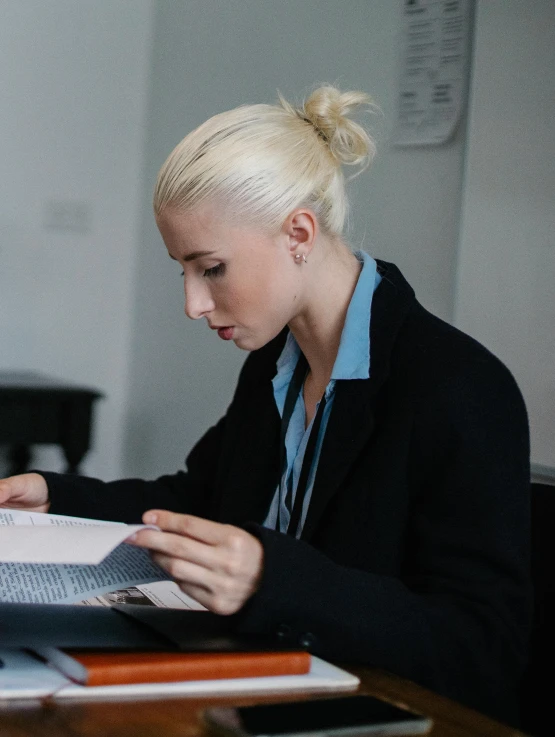 a woman sitting at a desk in front of a laptop computer, trending on reddit, private press, bleach blonde hair, tight bun, reading a book, side profile shot