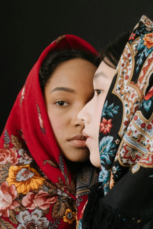 a couple of women standing next to each other, trending on unsplash, hyperrealism, patterned scarf, mixed race woman, face and skin is dark red, traditional russia