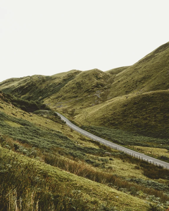 a car driving down a winding road in the mountains, an album cover, unsplash contest winner, grassy hills, muted green, scottish, ignant