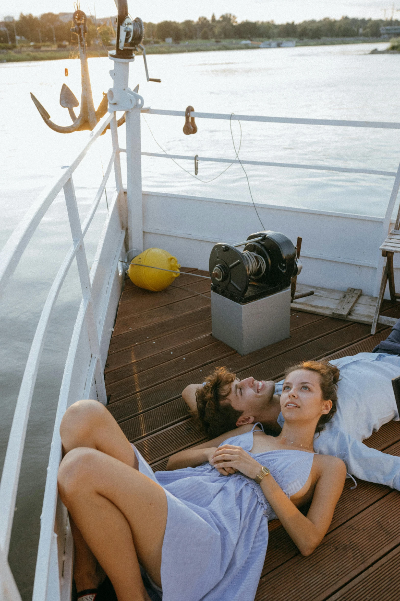 a man and woman laying on the deck of a boat, looking off into the distance, lying down, in majestic