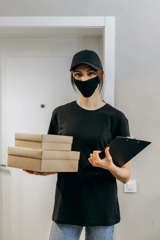 a woman wearing a face mask and carrying boxes, he is wearing a black t-shirt, pizza, dark visor covering face, papers