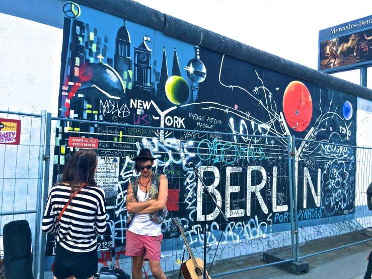 a group of people standing on the side of a building, graffiti, german chancellor, travel guide, a brightly colored, band