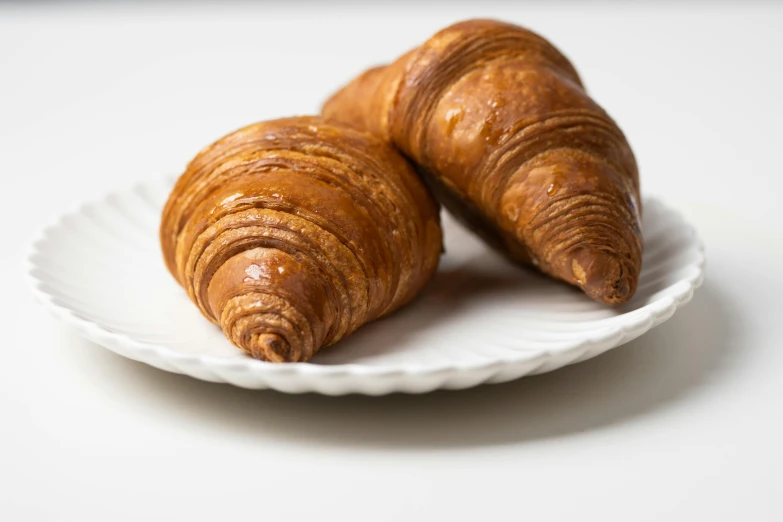 two croissants on a white plate on a table, unsplash, 3/4 front view, cone shaped, high quality product image”, vine twist