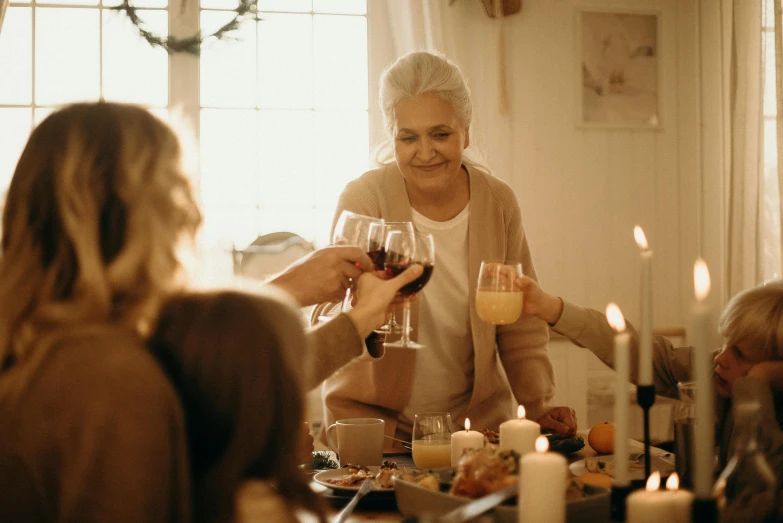 a group of people sitting around a table with wine glasses, grandma, holiday vibe, woman holding another woman, profile image