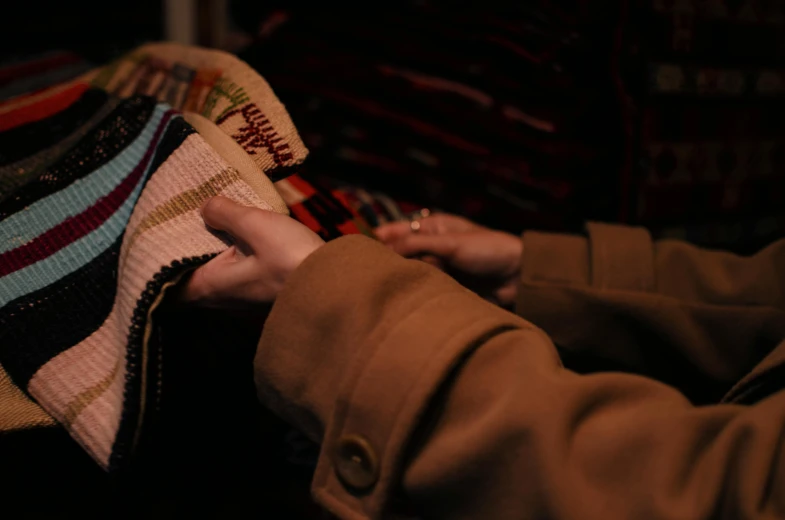 a close up of a person holding a sweater, a cross stitch, by Carey Morris, pexels contest winner, bags of money, during night, trading card game, brown