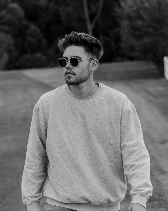 a black and white photo of a man holding a skateboard, inspired by Kyle Lambert, zac efron, wearing sweatshirt, with sunglass, prideful look