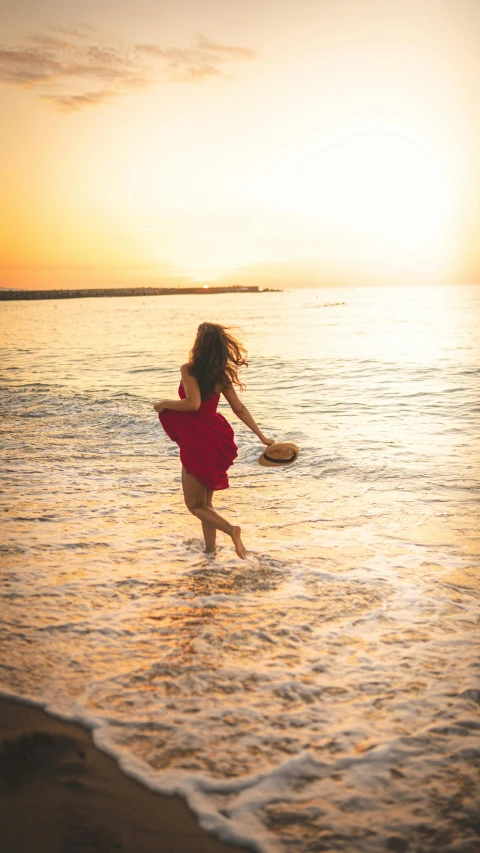 a little girl running into the ocean at sunset, an album cover, pexels contest winner, wearing a red sundress, beautiful woman, medium format. soft light, teenage girl