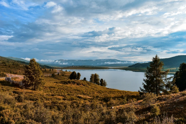 a large body of water sitting on top of a lush green hillside, by Muggur, unsplash, hurufiyya, lake in the distance, golden hour photo, grey, conde nast traveler photo