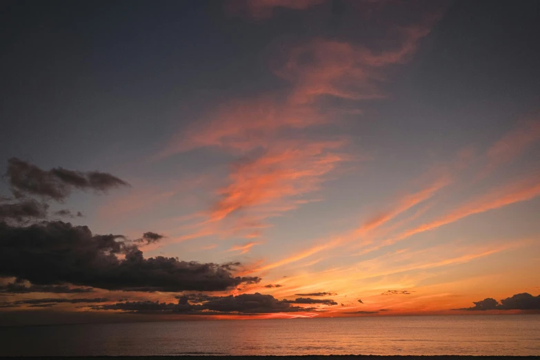 a bench sitting on top of a beach next to the ocean, unsplash contest winner, romanticism, orange and red sky, ceremonial clouds, dusk, evenly lit