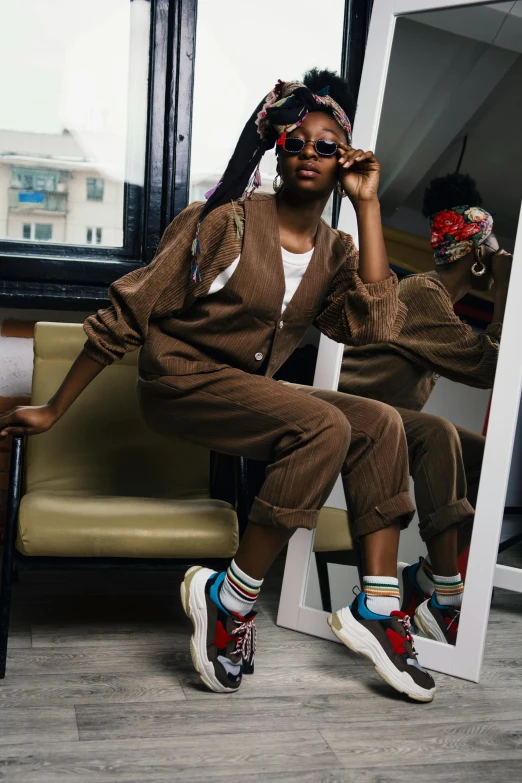 a woman sitting on a chair in front of a mirror, by Lily Delissa Joseph, trending on pexels, sneakers, beret and sunglasses, wearing a worn out brown suit, kano)