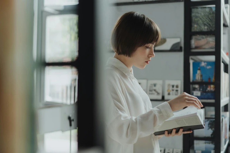 a woman reading a book in a library, a drawing, by Jang Seung-eop, pexels contest winner, wearing a white button up shirt, avatar image, side profile shot, standing near a window