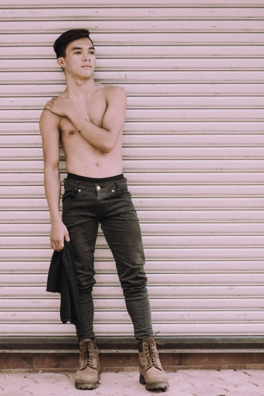 a shirtless man standing in front of a garage door, a colorized photo, trending on pexels, cai xukun, single character full body, solid background, androgynous person